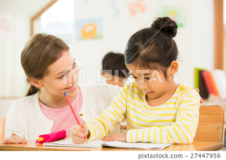 Female English Teacher Assisting A Young Student 27447956