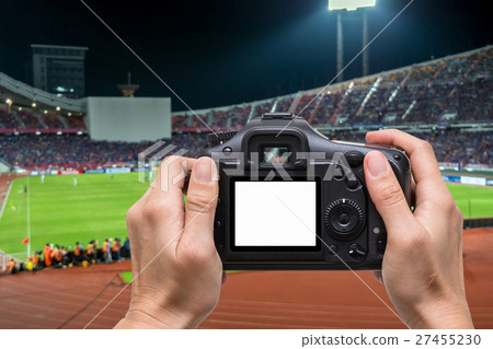Hand holding the camera over blurred of action photographer taking photo at player in Abstract blurred photo of soccer stadium, sport background concept 27455230