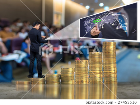 Asian Businessman standing on the stack of gold coins and using the tablet present the social network over Abstract blurred photo of conference hall or seminar room background,Business meeting concept Asian Businessman standing on the stack of gold coins and using the tablet present the social network over Abstract blurred photo of conference hall or seminar room background,Business meeting concept 27455510
