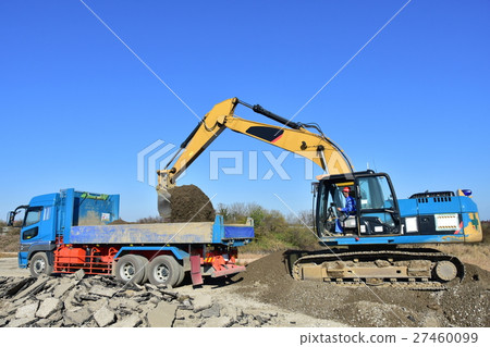 Hydraulic excavator loading earth and sand into a dump truck 27460099