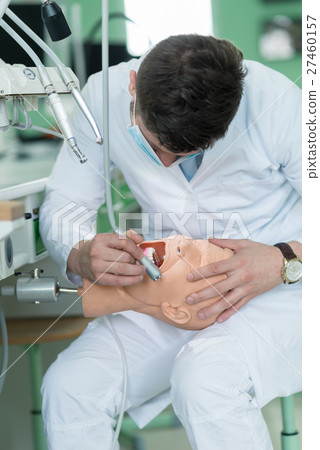 Male dental student practicing on doll. 27460157