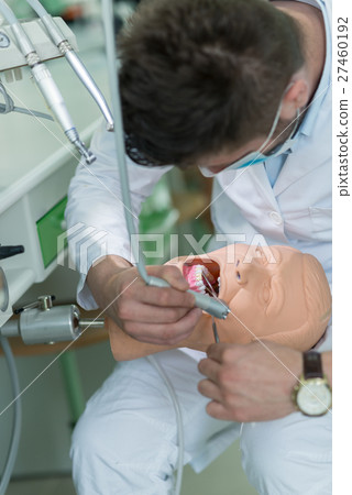 Male dental student practicing on doll. Male dental student practicing on doll. 27460192