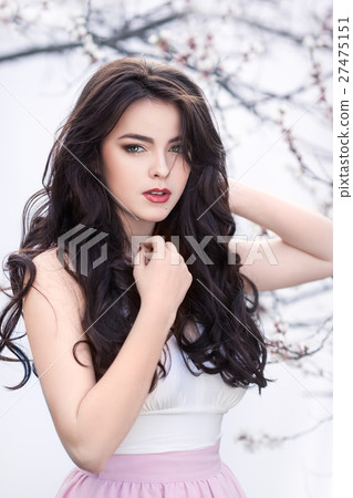 Beautiful girl standing at blossoming tree in the Beautiful girl standing at blossoming tree in the 27475151