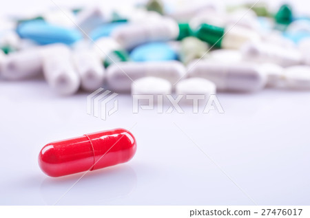 Red capsule closeup on a white surface Red capsule closeup on a white surface 27476017