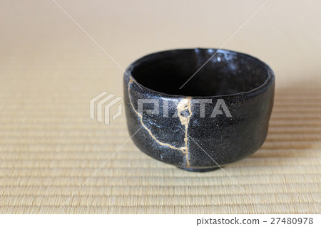A black matcha tea bowl and tatami mat repaired with kintsugi (gold repair): Traditional Japanese crafts embodying the spirit of wabi-sabi. 27480978