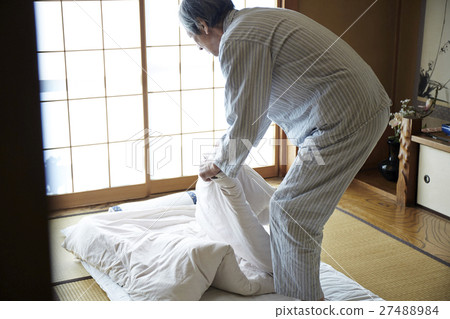 A man who folds an elderly male who folds bedding 27488984