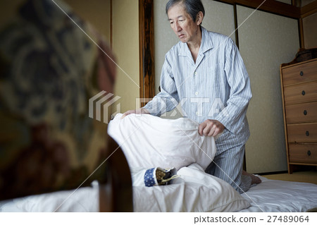 A man who folds an elderly male who folds bedding 27489064