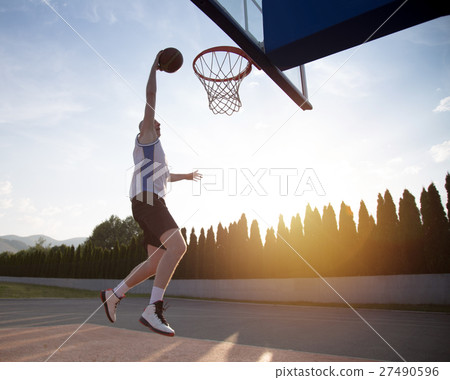 Young man jumping and making a fantastic slam dunk 27490596