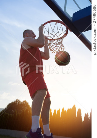 Young man jumping and making a fantastic slam dunk 27490686