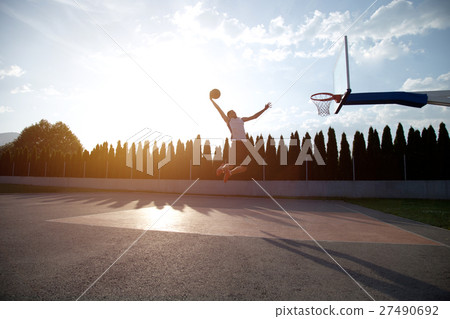 Young man jumping and making a fantastic slam dunk 27490692