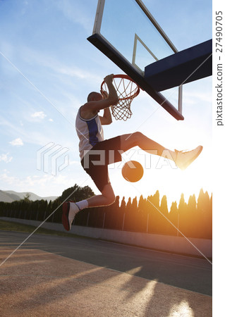 Young man jumping and making a fantastic slam dunk Young man jumping and making a fantastic slam dunk 27490705