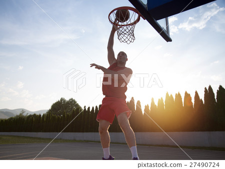 Young man jumping and making a fantastic slam dunk 27490724