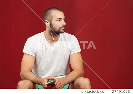 man sitting on a gym ball holding a phone after man sitting on a gym ball holding a phone after 27491036