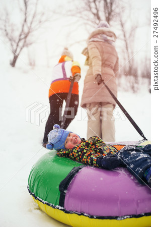 Happy smiling child lying on snow tube 27492496