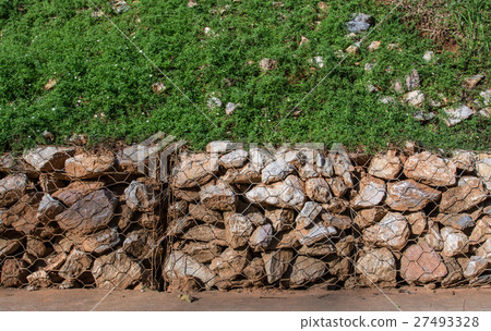 stone in metallic net with green grass stone in metallic net with green grass 27493328