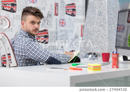 Young man taking notes from his laptop to his 27494530