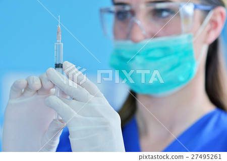 The surgeon dentist in mask holding syringe for The surgeon dentist in mask holding syringe for 27495261