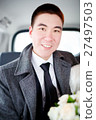 The groom in a winter coat sitting in the car with 27497503