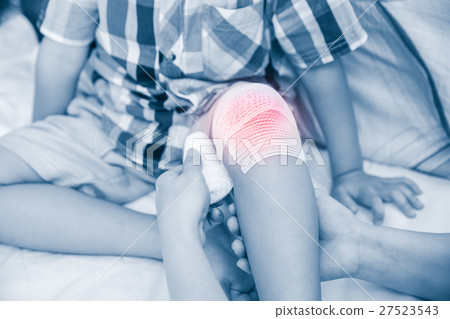 Child injured. Mother bandaging son's knee. 27523543