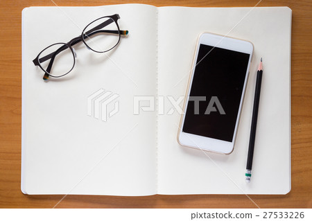 Cell phone, eyeglasses, and pencil on white notebook 27533226