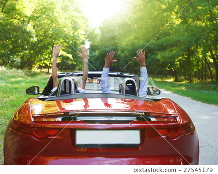 Happy free couple driving in red retro car  27545179