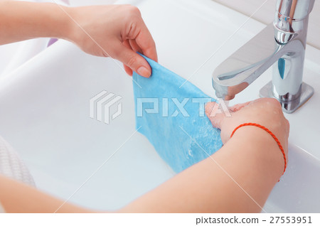 Female hands cleaning tap with orange cloth 27553951