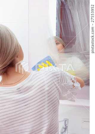 Young lady wiping mirror with special cleaning 27553952