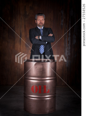Mature businessman and barrel of crude oil on dark Mature businessman and barrel of crude oil on dark 27558526