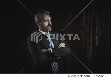 Portrait of a mature businessman on black 27558598