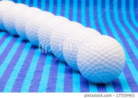 White golf balls on blue striped table. 27559463
