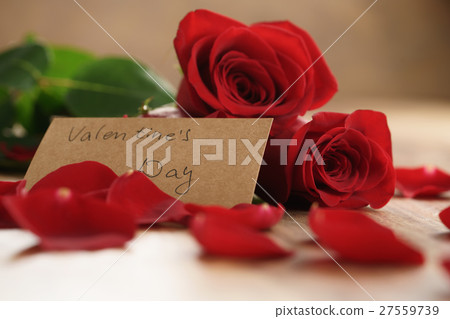three red roses with petals on wood table and 27559739