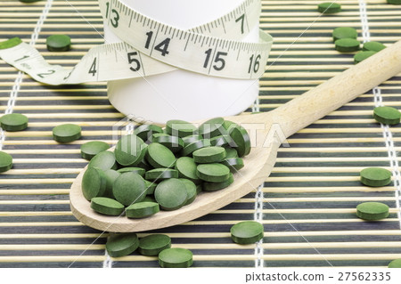 Spirulina,chlorella pills on wood spoon and measur 27562335