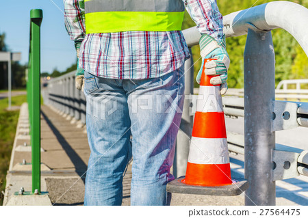 Road construction worker with traffic cone near hi 27564475