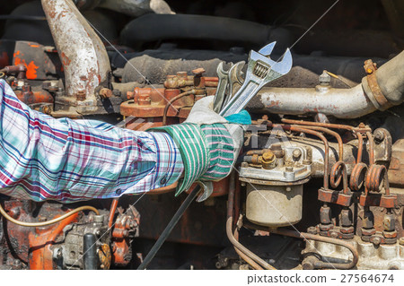 Man's hand with adjustable wrench near old diesel Man's hand with adjustable wrench near old diesel 27564674