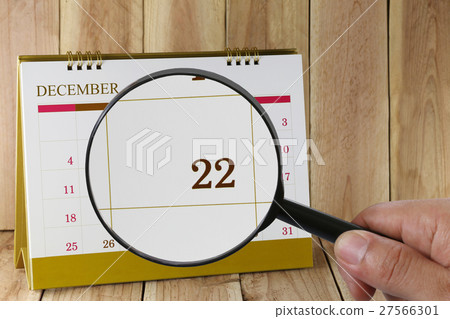 Magnifying glass in hand on calendar you can look Twenty-two date of month,Focus number Twenty-two in December. 27566301