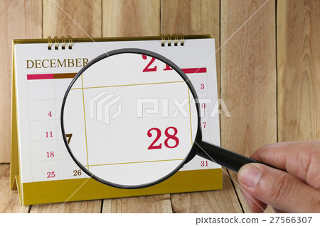 Magnifying glass in hand on calendar you can look Twenty-eight date of month,Focus number Twenty-eight in December. Magnifying glass in hand on calendar you can look Twenty-eight date of month,Focus number Twenty-eight in December. 27566307