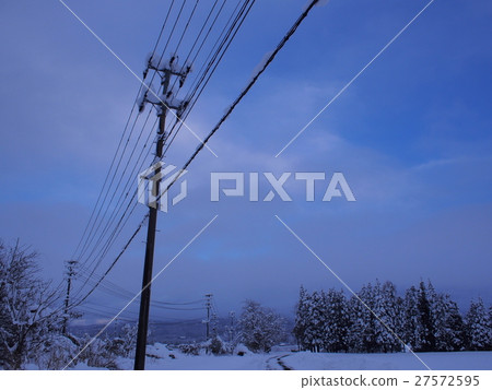 Snow piled on utility pole and electric wire 27572595