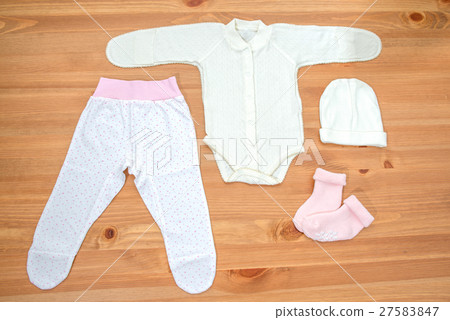 Clothes for newborn girl on a wooden background Clothes for newborn girl on a wooden background 27583847