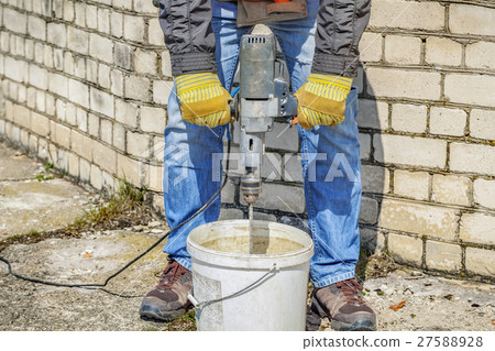 Builder stir plaster near to the unfinished buildi 27588928