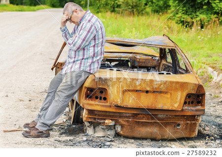 Stressful man on burned down car wreck on the side Stressful man on burned down car wreck on the side 27589232