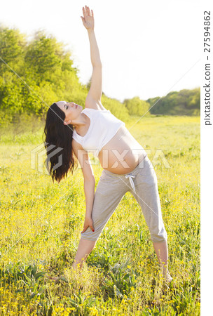 Pregnant woman doing yoga in nature outdoors 27594862
