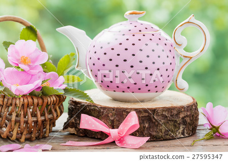 Tea kettle and basket with pink wild roses. Tea kettle and basket with pink wild roses. 27595347