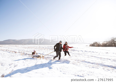 Father and mother pulling daughter on sledge Father and mother pulling daughter on sledge 27617995