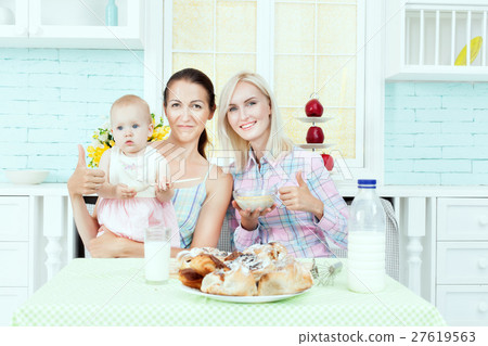 Two women feeding child. 27619563