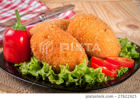 three fried breaded cutlet with lettuce on a black three fried breaded cutlet with lettuce on a black 27622925