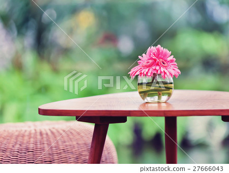 Pink flowers in vase on table in the garden.  27666043