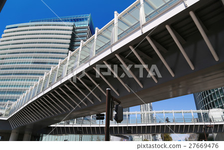 A pedestrian bridge in a building street on a sunny day 27669476