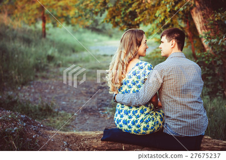 Loving couple embracing sitting in the woods. Loving couple embracing sitting in the woods. 27675237