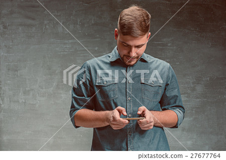 The young smiling caucasian businessman on gray 27677764