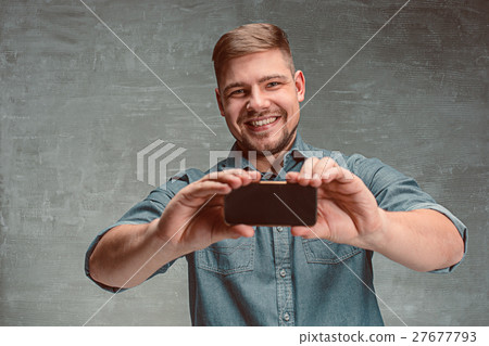 The young smiling caucasian businessman on gray 27677793
